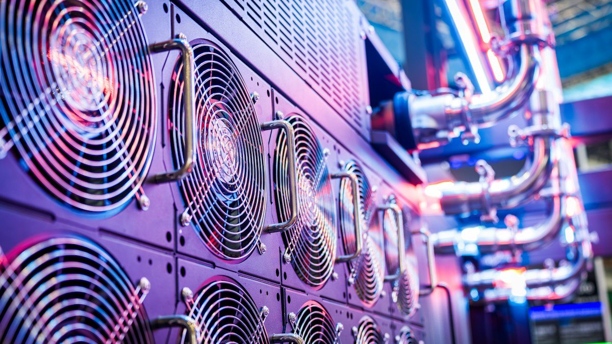Close-up of server cooling fans and liquid piping in a data center. Photo by Winston Chen on Unsplash. Source: https://unsplash.com/photos/close-up-of-server-cooling-fans-in-a-vibrant-data-center-iZe21DzHnUg (Unsplash License).