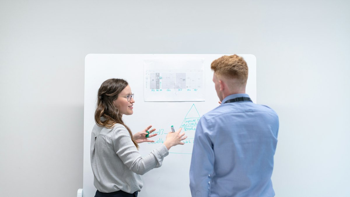 Photo by ThisisEngineering on Unsplash. Source: https://unsplash.com/photos/two-colleagues-discussing-ideas-at-whiteboard-uOhBxB23Wao (Unsplash License).