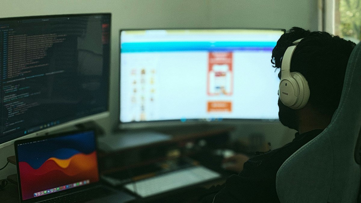 Photo by Ilham Malik on Unsplash. Source: https://unsplash.com/photos/a-person-works-on-computer-with-multiple-monitors-WbLJd4M88I8 (Unsplash License).