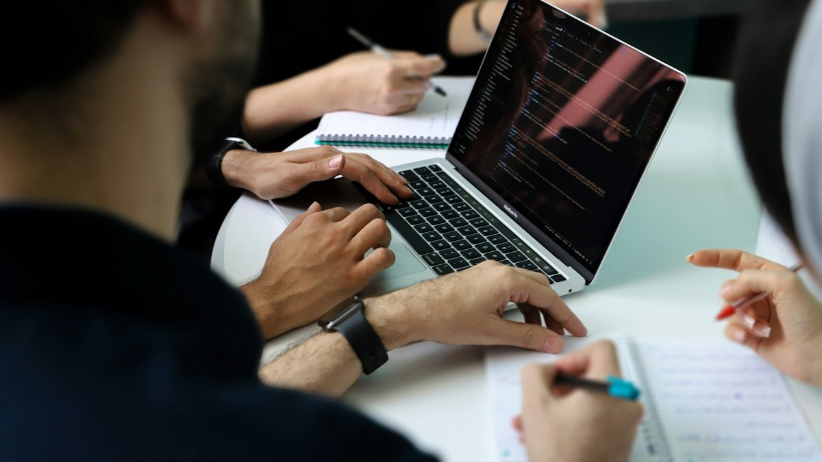 Photo by Fatemeh Rezvani on Unsplash. Source: https://unsplash.com/photos/a-group-of-people-sitting-around-a-laptop-computer-MnPWB-ybjHQ (Unsplash License).