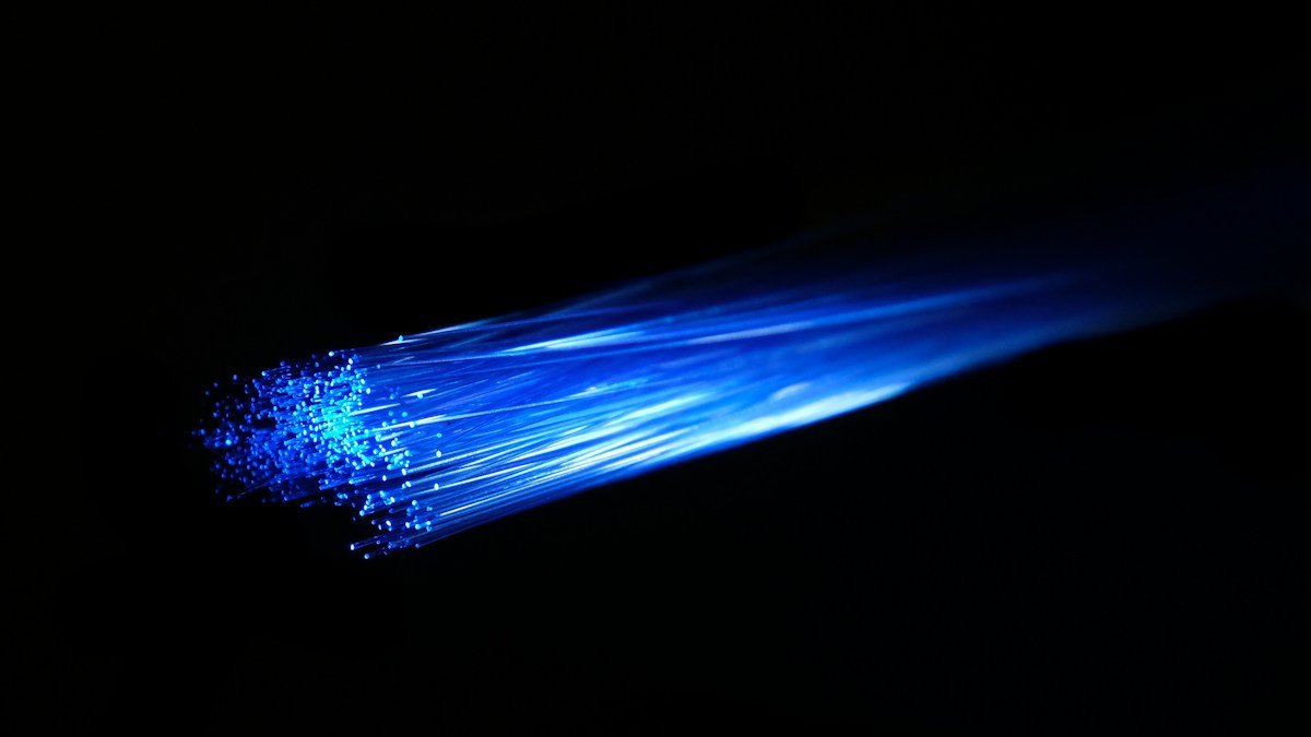 Blue fiber optic strands glowing against a dark background. Photo by Compare Fibre on Unsplash. Source: https://unsplash.com/photos/blue-and-white-light-in-dark-room-INNsF0Zz_kQ (Unsplash License).