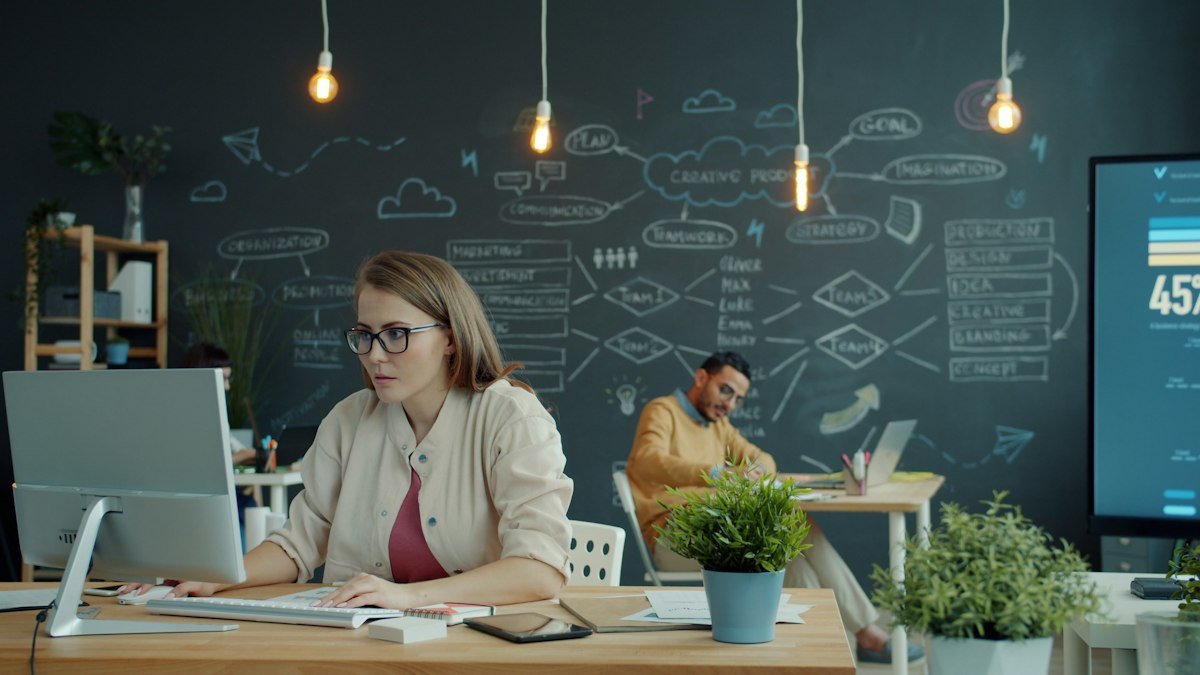 Photo by Vitaly Gariev on Unsplash. Source: https://unsplash.com/photos/woman-working-on-computer-in-modern-office-with-chalkboard-rU1_DCersNs (Unsplash License).