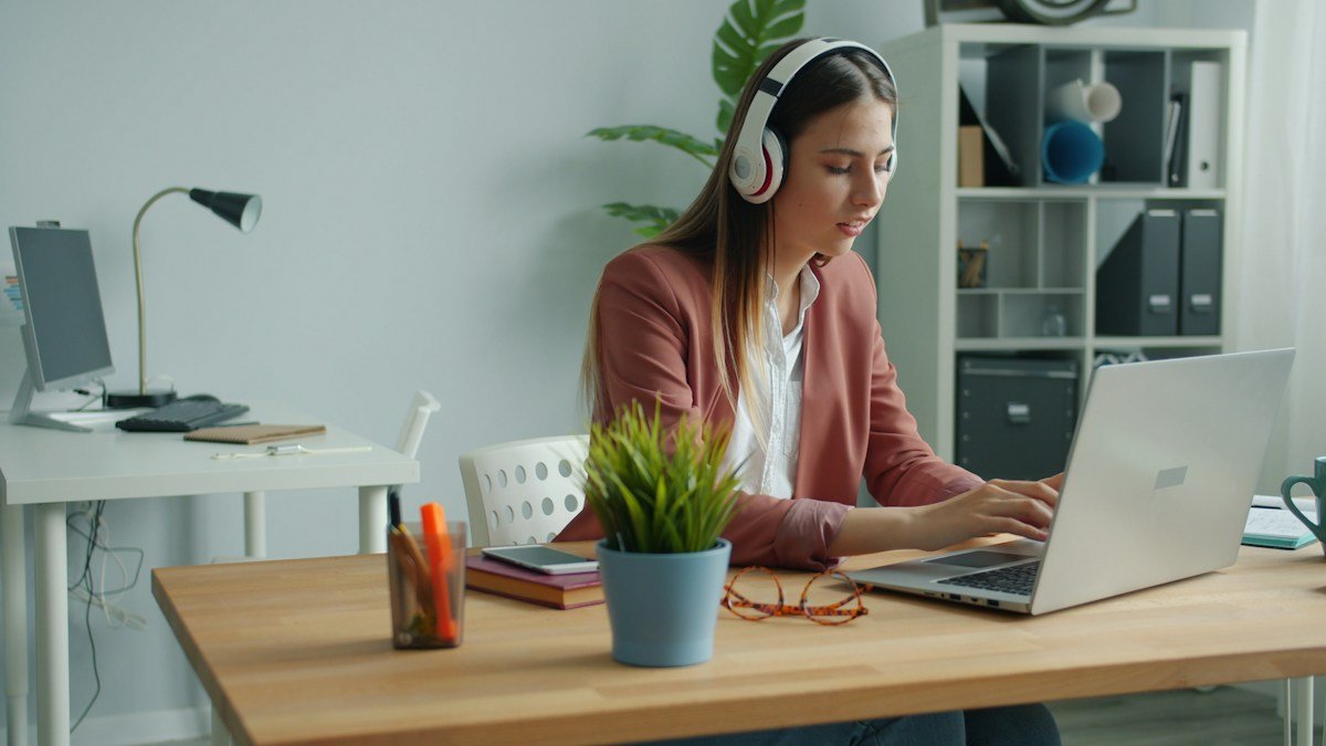 Photo by Vitaly Gariev on Unsplash. Source: https://unsplash.com/photos/woman-wearing-headphones-working-on-laptop-at-desk-8Pw0ZjbgQ9w (Unsplash License).