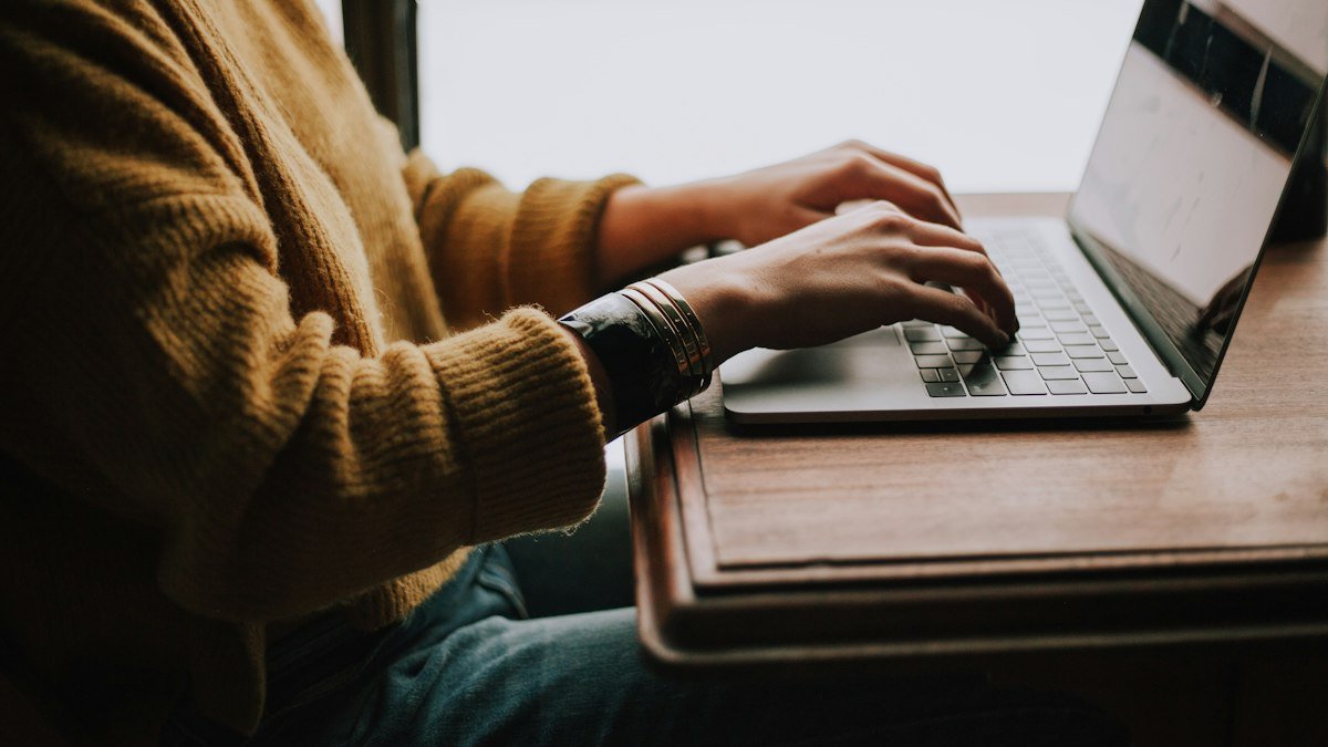 Photo by Christin Hume on Unsplash. Source: https://unsplash.com/photos/person-sitting-front-of-laptop-mfB1B1s4sMc (Unsplash License).