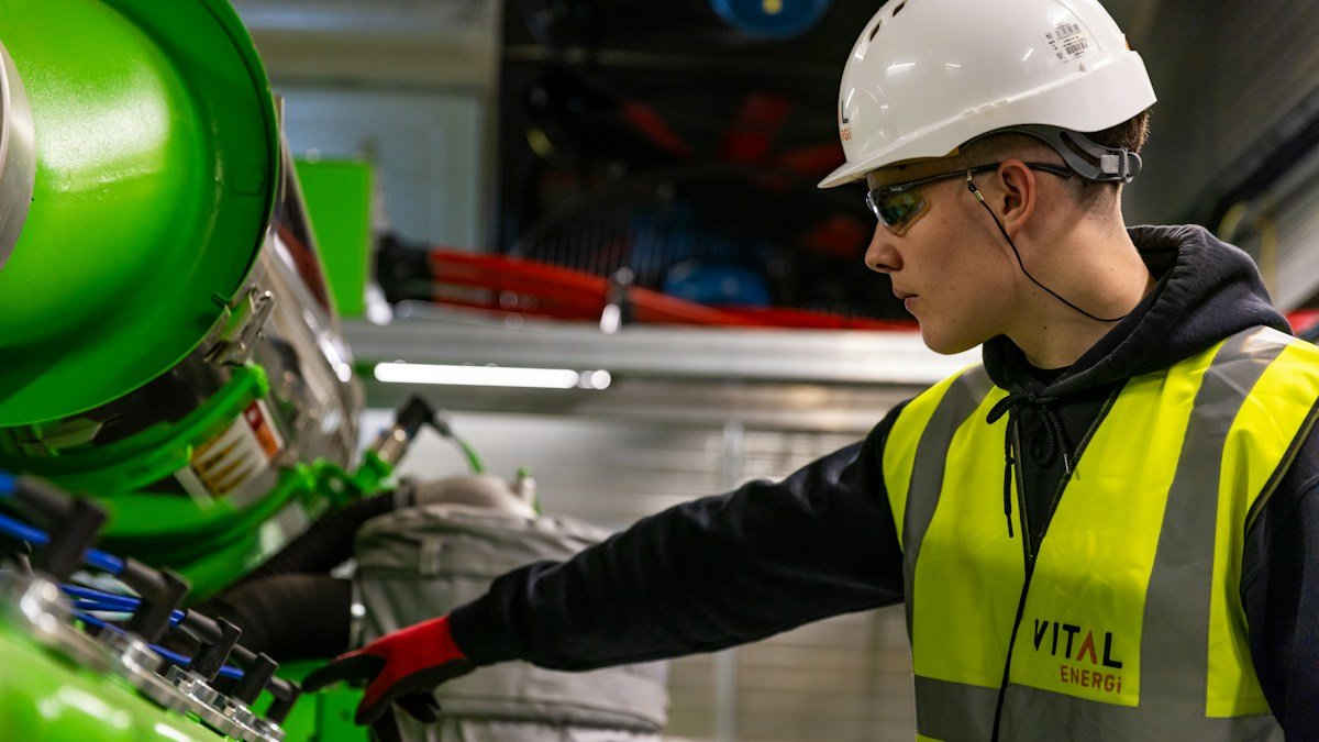 A young engineer in a hard hat and safety vest works on industrial equipment. Photo by ThisisEngineering on Unsplash. Source: https://unsplash.com/photos/a-man-in-a-hard-hat-and-safety-vest-working-on-a-machine-9kYa--GkBPs (Unsplash License).