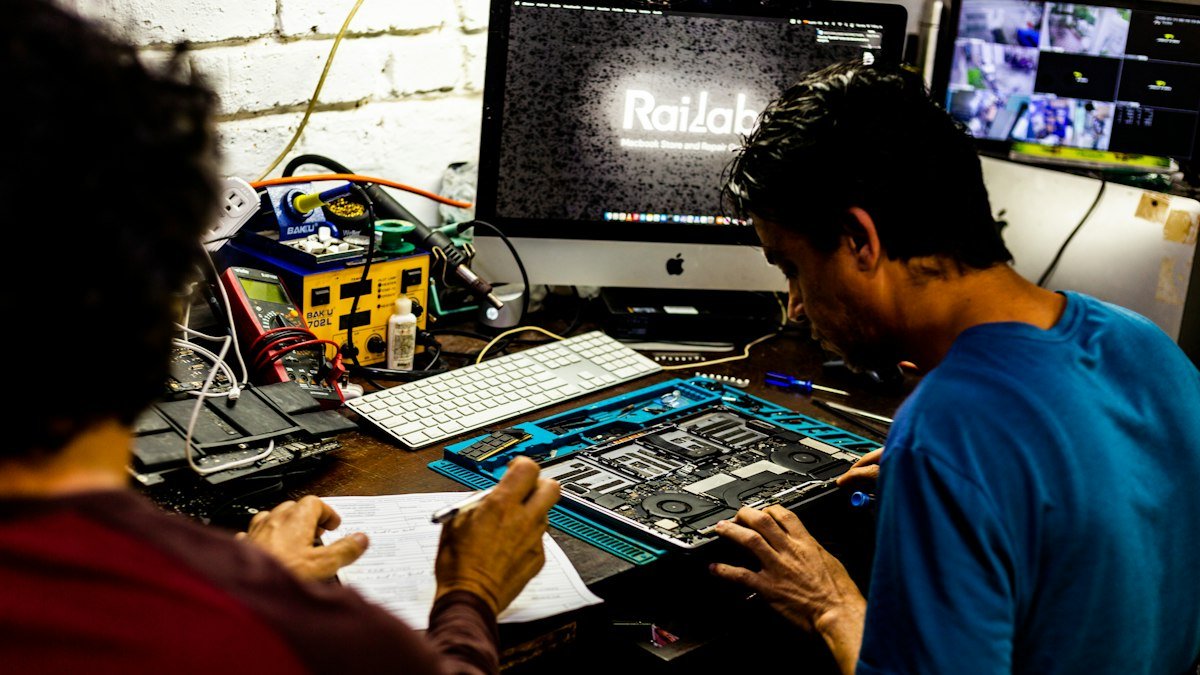 Engineers working together on a computer motherboard in a lab. Photo by Ricardo IV Tamayo on Unsplash. Source: https://unsplash.com/photos/two-men-working-on-a-computer-motherboard-nApaD08bFAE (Unsplash License).