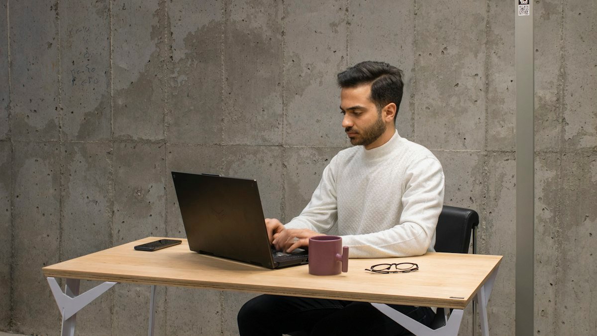 Photo by Mina Rad on Unsplash. Source: https://unsplash.com/photos/a-man-sitting-at-a-table-using-a-laptop-computer-eR3W3BouGL4 (Unsplash License).