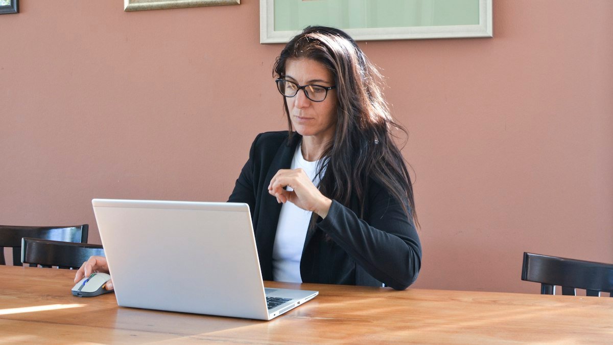 Photo by Aleksei Zhivilov on Unsplash. Source: https://unsplash.com/photos/woman-in-glasses-working-on-a-laptop-at-a-table-A6M3aowKR6I (Unsplash License).