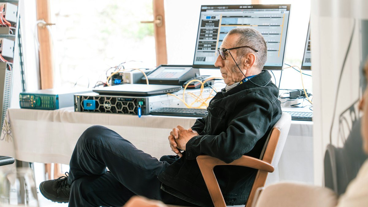 Photo by Raymond Sime on Unsplash. Source: https://unsplash.com/photos/a-man-sitting-at-a-desk-with-computer-equipment-DP8OyOZGd9I (Unsplash License).