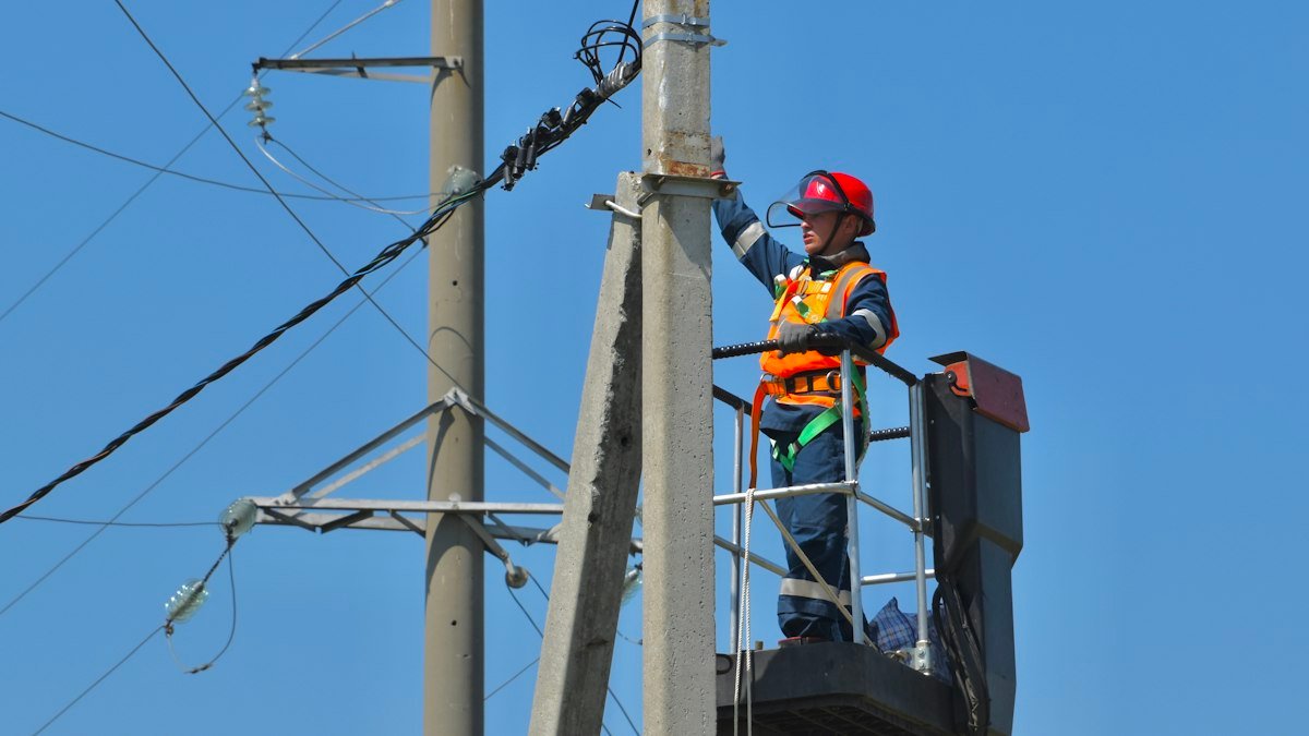 Photo by Антон Дмитриев on Unsplash. Source: https://unsplash.com/photos/a-man-standing-on-top-of-a-metal-pole-next-to-power-lines-j4whez6CEL0 (Unsplash License).