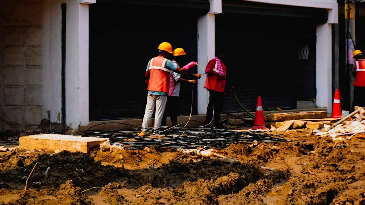 Photo by Adhitya Sibikumar on Unsplash. Source: https://unsplash.com/photos/construction-workers-in-hard-hats-near-a-building-9j0HxsTPBlk (Unsplash License).