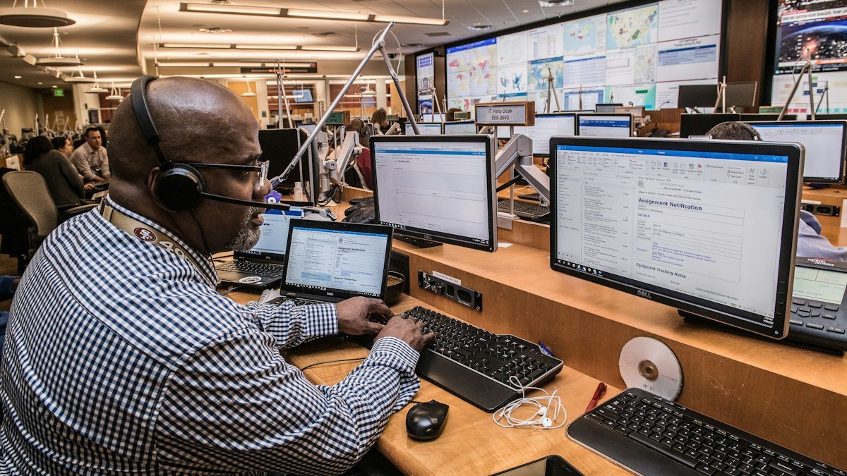 An operator at a multi monitor workstation reviewing system dashboards