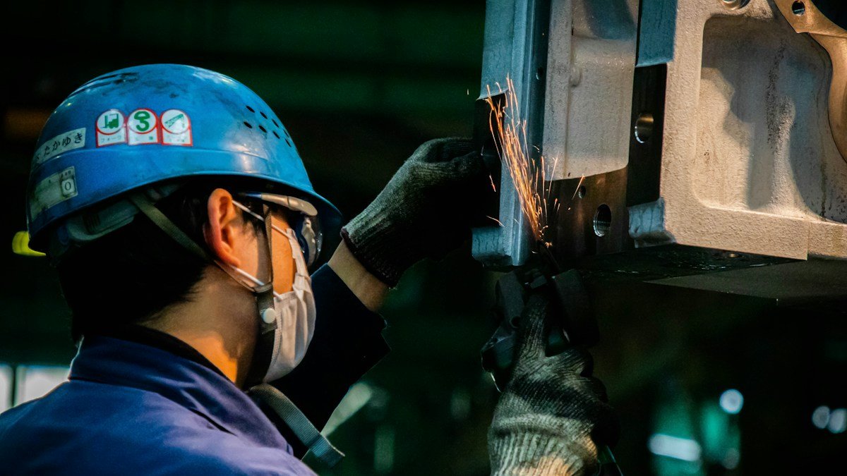 Photo by eltonchen on Unsplash. Source: https://unsplash.com/photos/man-in-blue-jacket-and-red-helmet-holding-black-and-orange-power-tool-DXc9sBlYbgs (Unsplash License).