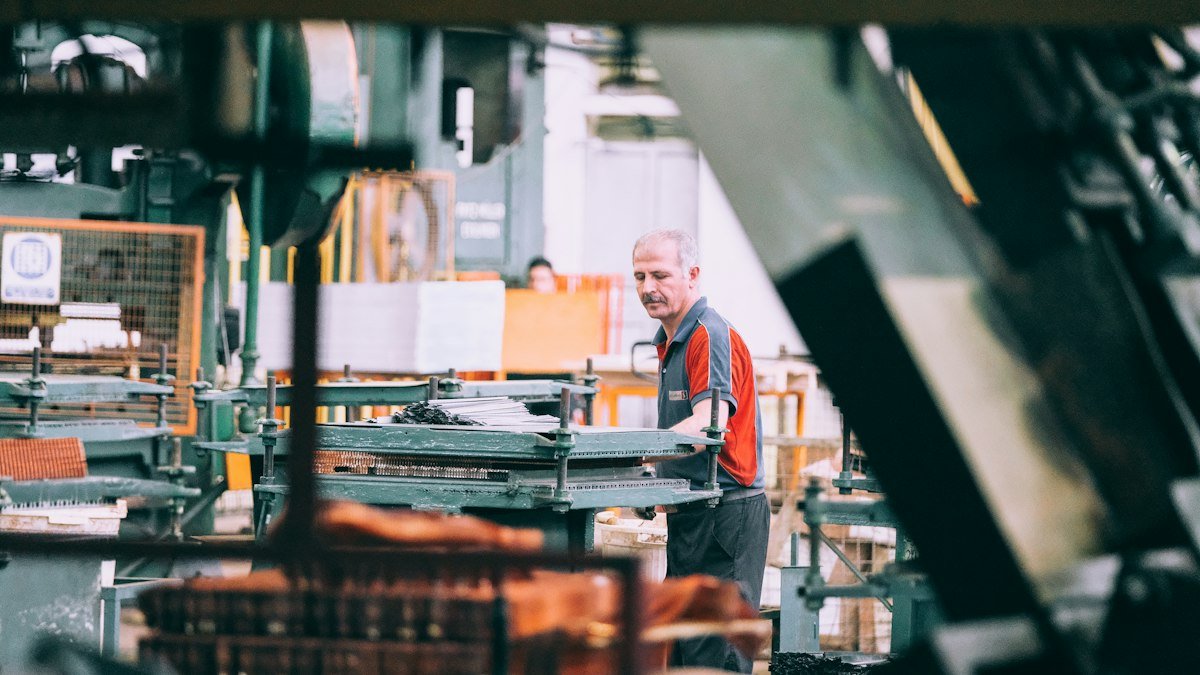 Photo by Sam Moghadam on Unsplash. Source: https://unsplash.com/photos/man-operating-industrial-factory-machinery-bN_aaTKfwM0 (Unsplash License).
