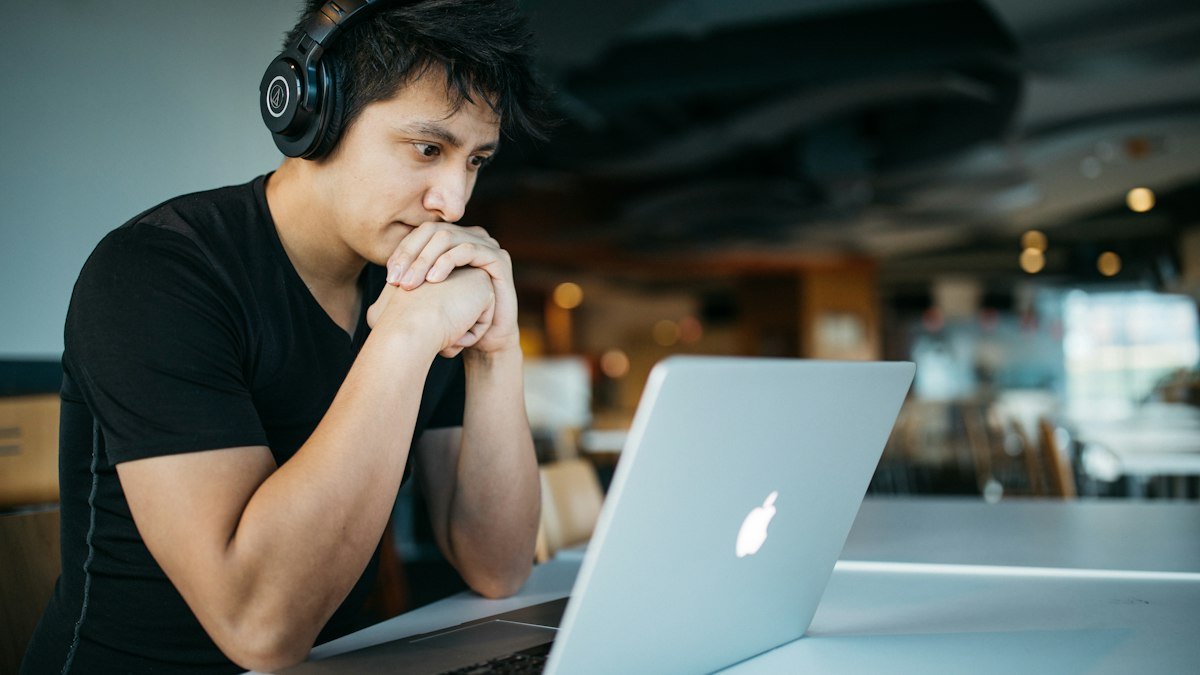 Photo by Wes Hicks on Unsplash. Source: https://unsplash.com/photos/man-wearing-headphones-while-sitting-on-chair-in-front-of-macbook-4-EeTnaC1S4 (Unsplash License).