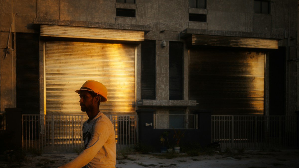 Photo by Infinara on Unsplash. Source: https://unsplash.com/photos/man-in-hard-hat-walks-past-industrial-building-at-sunset-ApthFQI_9bo (Unsplash License).