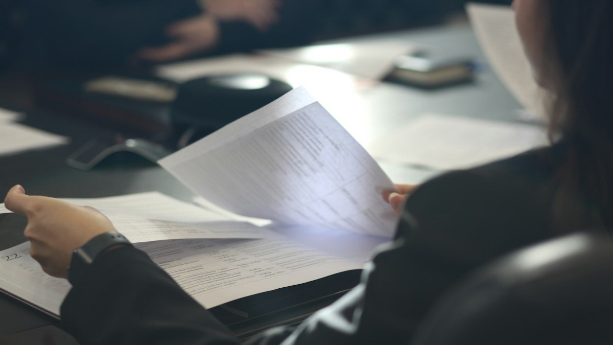 Photo by Anastassia Anufrieva on Unsplash. Source: https://unsplash.com/photos/a-woman-sitting-at-a-table-reading-a-paper-ecHGTPfjNfA (Unsplash License).